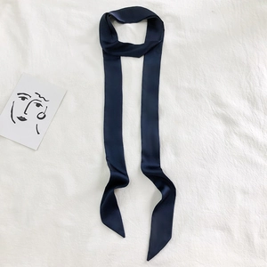 Detail of a 2-meter navy blue silk scarf on a white textured fabric with an art card