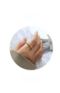 Détail d'une bague dorée avec une texture martelée sur un fond artistique blanc épuré