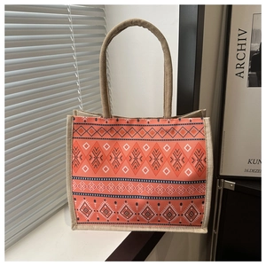 Detail of bohemian orange tote bag featuring ethnic geometric patterns and woven handles