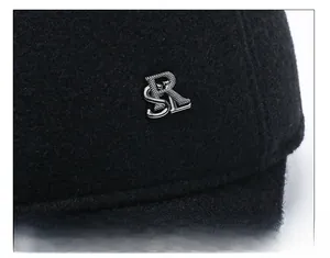Dettaglio del tessuto in lana nera con logo metallico argento 'SRL' su un cappello uomo