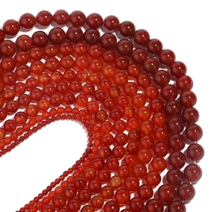 Polished natural red agate loose round beads in various sizes arranged on white backdrop