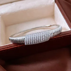 Bracciale rigido argentato con zirconi incastonati in una scatola portagioielli marrone