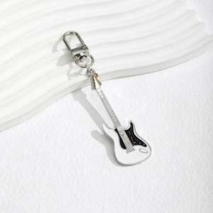 Detailed macro view of an electric guitar keychain with silver hardware and white finish