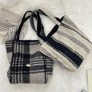Detail of plush lamb wool tote bags featuring stylish plaid patterns and golden brand logo