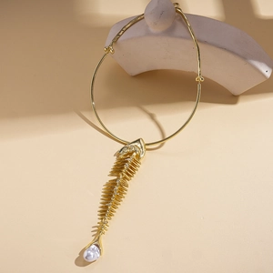 Detailed close-up of golden fishbone pendant with a baroque pearl on a metal choker