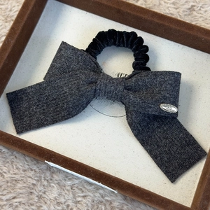 Detail of dark grey wool knit bow hair tie with a gold Love is Forever metal charm