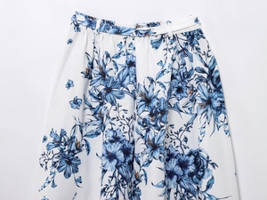 Detail of white floral midi skirt with blue lily pattern and pleated waist texture