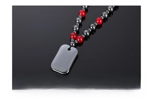 Macro detail of hematite beads and red agate accents on a polished rectangular tag necklace