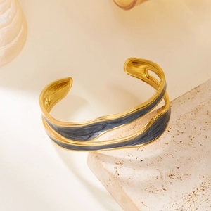 Macro detail of a double-layered gold and black enamel cuff bracelet on natural stone