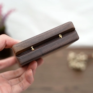 Close-up of premium dark wood jewelry box featuring a shiny golden metal hinge detail