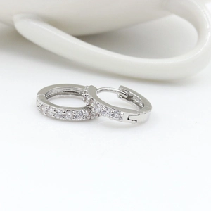 Macro view of silver geometric earrings with clear zircon stones on a white background