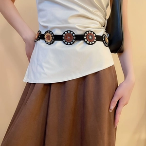 Detail of bohemian leather waist belt featuring geometric floral buckles and vintage studs