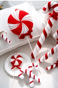 Detail of red and white velvet Christmas candy cane hanging ornaments with soft bows
