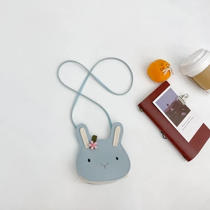 Flat lay of a blue rabbit mini crossbody bag for kids with floral ear detail on white background