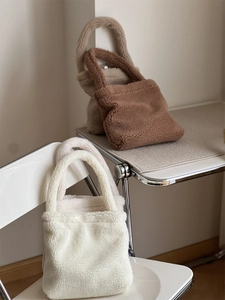 Close-up of plush faux fur tote bags in white, cream, and brown on a minimalist chair