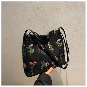 Close-up of black knit tote bag featuring vibrant colorful floral embroidery details