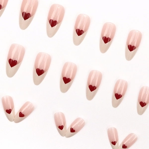 French almond press-on nails in soft pink with creamy white tips and red heart accents