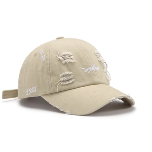 Distressed beige baseball cap with embroidery and ripped details on a white background