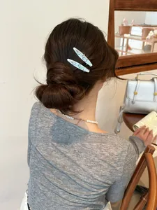 Detail view of light blue acetate dog hair clips with 'egg' relief on a female model