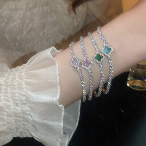 Detail of four-leaf clover bracelets set with colored stones and shimmering zircon stones