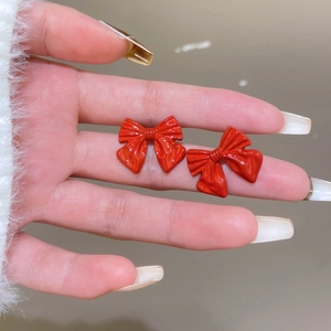 Close-up of vibrant red bow-shaped earrings with a glossy finish and realistic ribbon folds