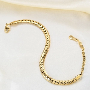 Macro shot of gold-plated 6mm Cuban link bracelet on beige silk background