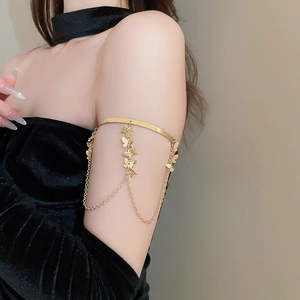 Close-up of golden butterfly fringe arm cuff with metallic chains on a model arm