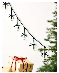 Detail of dark green velvet bows and golden bells hanging on a Christmas decorative string