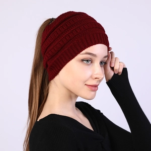 Detail of dark red knitted headband with a ponytail hole design for winter warmth