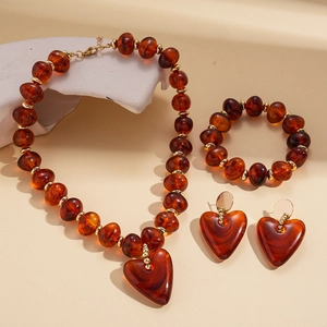 Macro view of amber heart pendant set with marbled acrylic beads and gold spacers