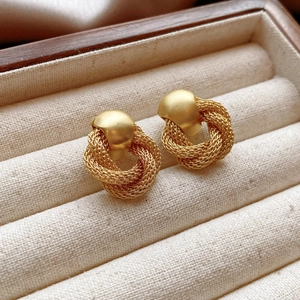 Macro detail of gold woven drop earrings with matte finish in a velvet jewelry box