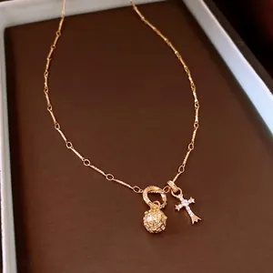 Vintage style gold necklace with a hollow floral bead and diamond cross pendant
