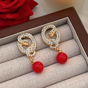 Detail of snake drop earrings with sparkling crystals and a red bead in a gift box