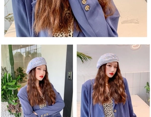Detail of sequin beret in iridescent purple shown on a model with blue blazer