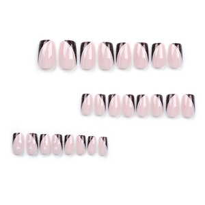 French tip press-on nails with nude base, black glitter accents, and white heart patterns