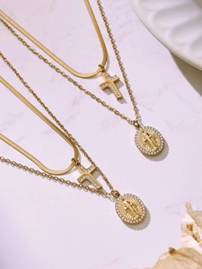Detailed view of layered gold necklaces with zircon cross and religious coin pendants