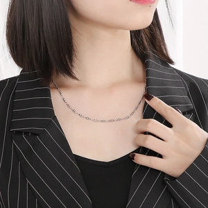 Detailed view of a minimalist silver beaded necklace worn by a model in professional attire