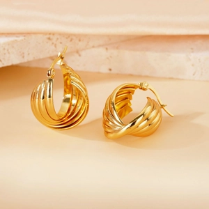 Macro shot of 18K gold-plated ribbed hoop earrings with a modern layered twist design