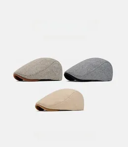 Three British style herringbone tweed newsboy caps in brown, gray, and beige colors