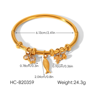 Détail d'un bracelet en acier doré 18 carats avec breloques étoile, poisson et palmier