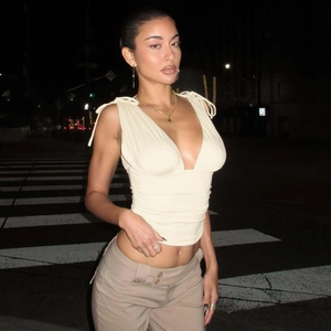 Dettaglio del crop top con scollo a V profondo, texture increspata e spalline annodate