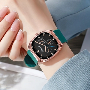 Detail of a square rose gold watch with green silicone strap on a woman's wrist