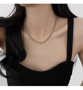 Close-up of a silver beaded pearl necklace worn by a model in a French vintage style
