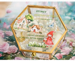 Close-up of a hexagonal gold glass jewelry box decorated with vintage fairytale stickers