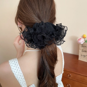 Détail d'un chouchou en dentelle noire porté en queue de cheval pour un style élégant