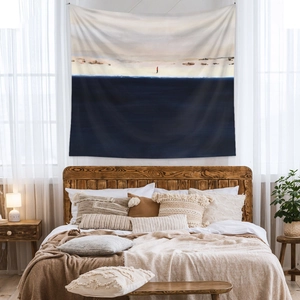 Minimalist bohemian tapestry with deep blue and beige shapes hung over a wooden bed frame