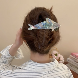 Detail view of a blue marble acetate dolphin hair claw clip worn in a messy bun