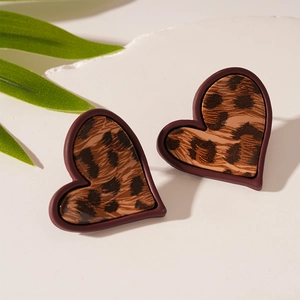 Détail de boucles d'oreilles en forme de cœur à imprimé léopard avec bordure rouge sur pierre