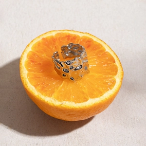 Macro detail of silver lava textured irregular ring placed inside a fresh orange slice