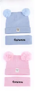 Close-up of knit baby beanie with double faux fur pom-poms and embroidered love me more headband